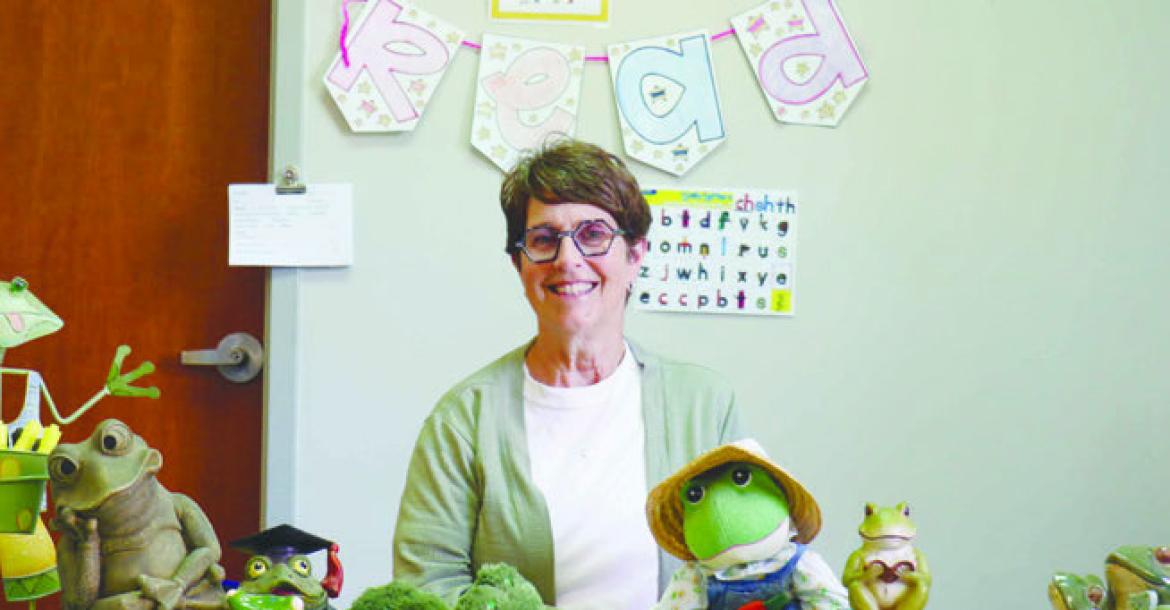 KELLIE SEWARD sits at a desk in her room at St. Paul Elementary School surrounded by just a few of the frogs she has been given by her students, their families, and her colleagues. When she started teaching forty-one years ago, the retiree had been asked to choose a theme for her classroom. She chose frogs, and the association has stuck. Photo by Michael Rother