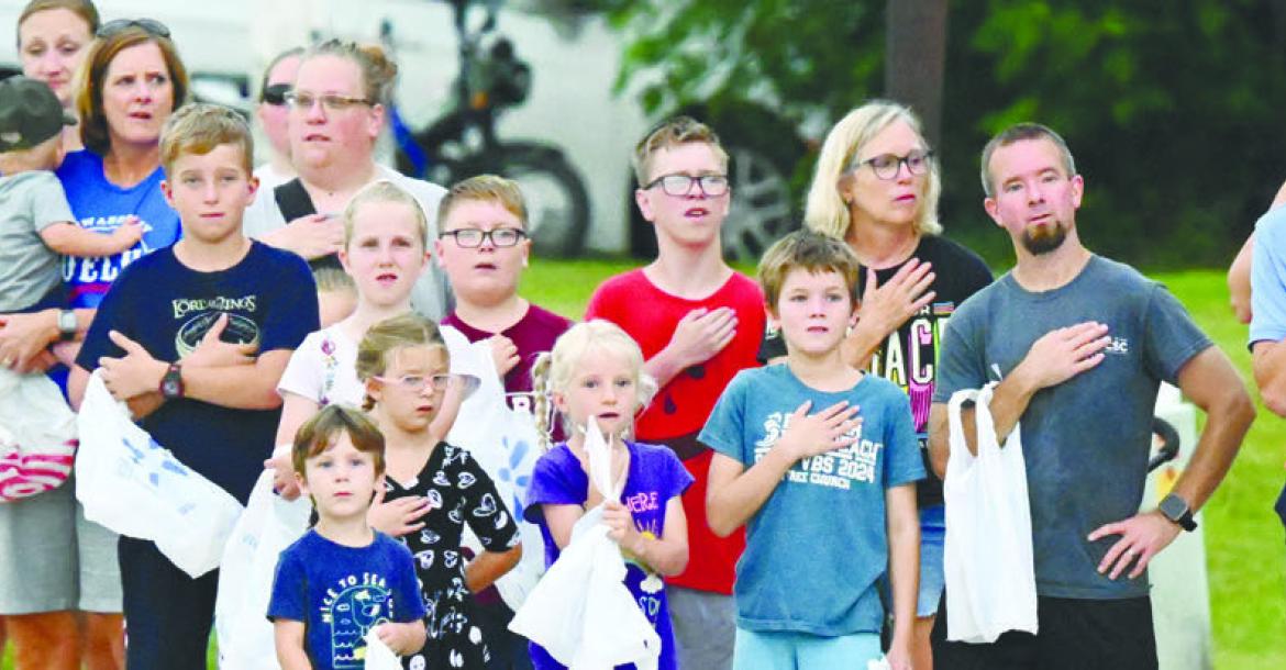 PARADEGOERS gathered along the parade route along Deleware Street in downtown Boelus on Saturday stand at attention for the playing of the national anthem prior to the start of the parade. Photos by Michael Happ