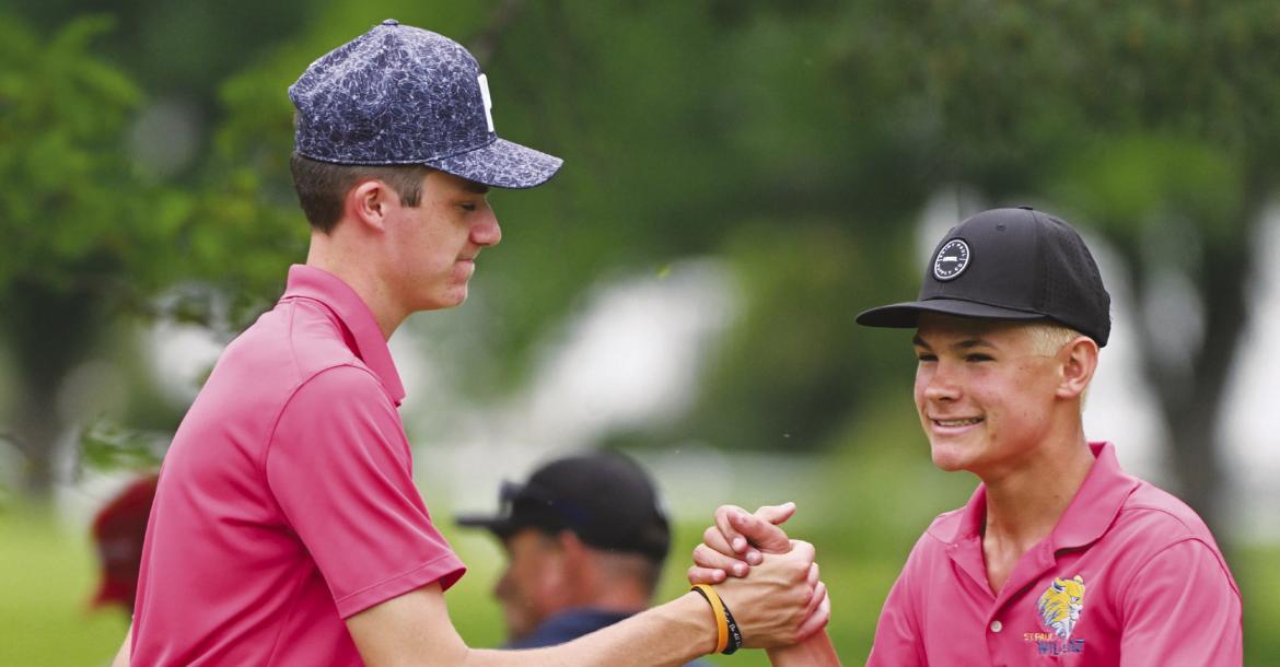MADDOX QUINN congratulates Casen Kavan after the sophomore sinks a putt on the eighteenth hole of the state championship course on Thursday afternoon in Grand Island.